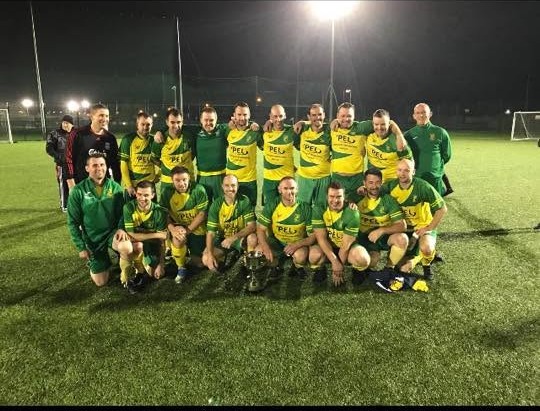Crettyard United squad with a trophy under floodlights on the astro pitch