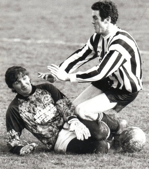 Goalkeeper smothering the ball at a striker's feet