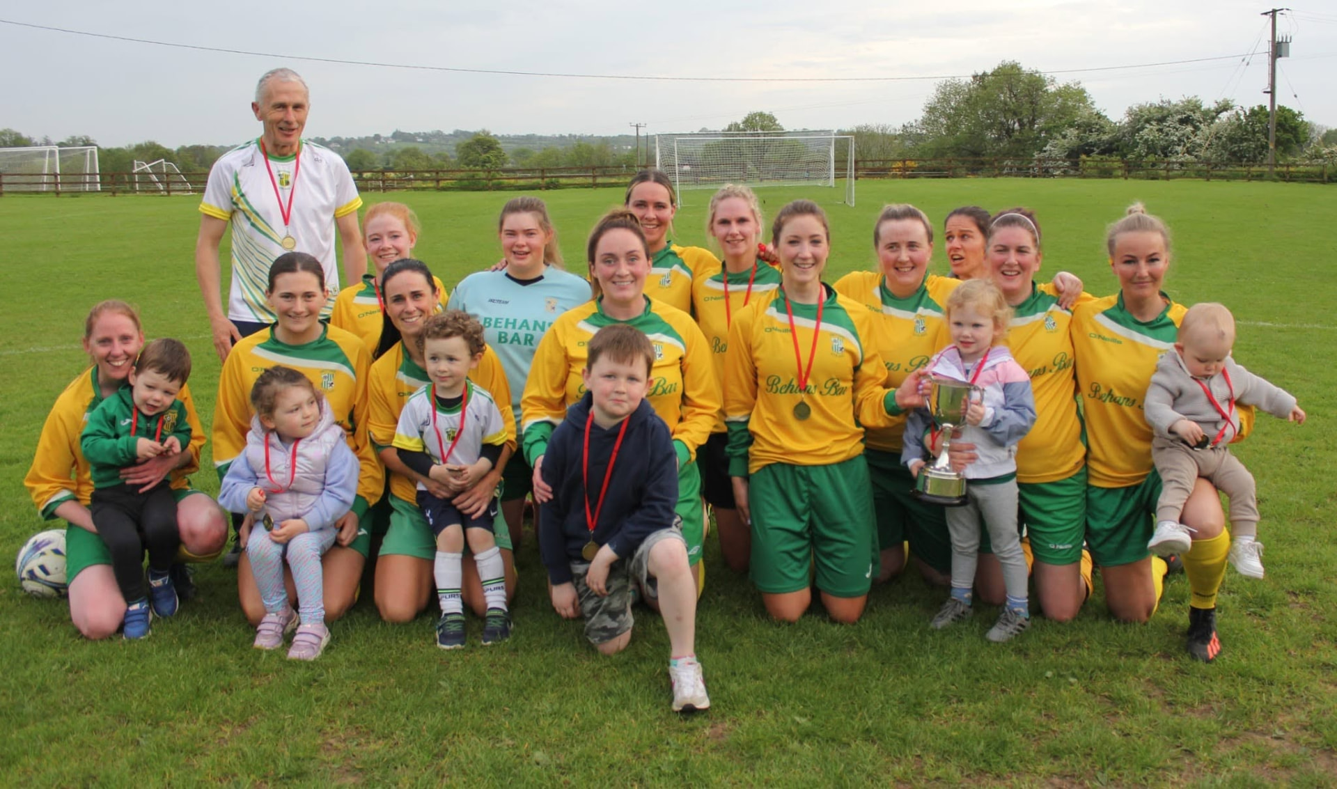 Crettyard United ladies team with medals and the cup alongside families