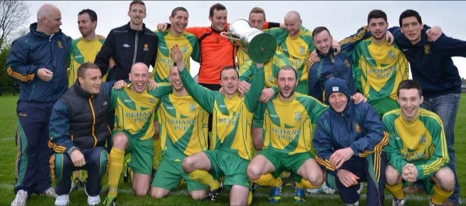 Crettyard United players and management celebrating with the cup in Behans Pub kit
