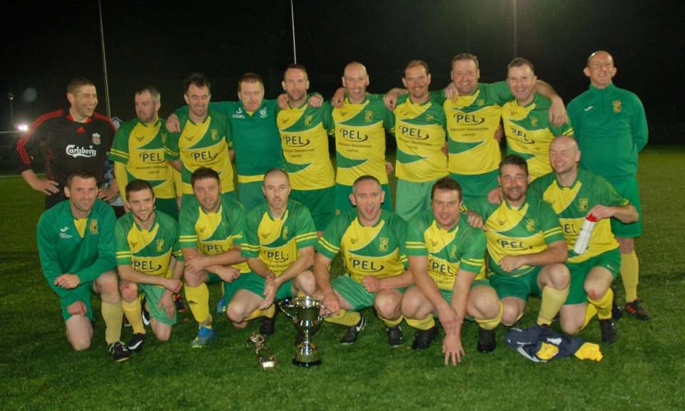 Crettyard United squad celebrating with trophies under floodlights in PEL kit