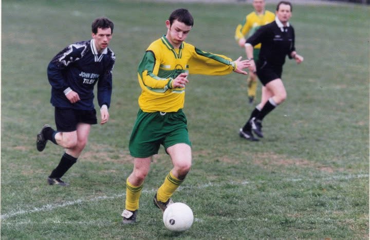 Young Crettyard United player on the ball with the referee behind