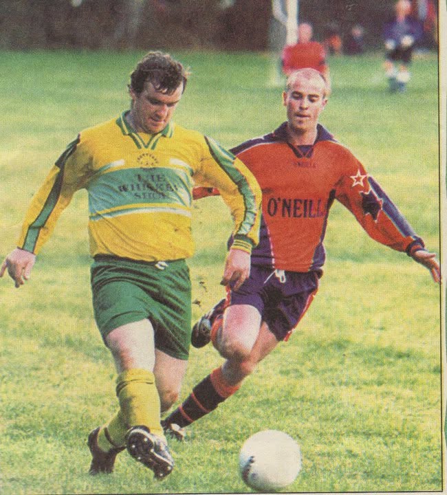 Crettyard United player in The Whiskey Shop kit shielding the ball from an opponent