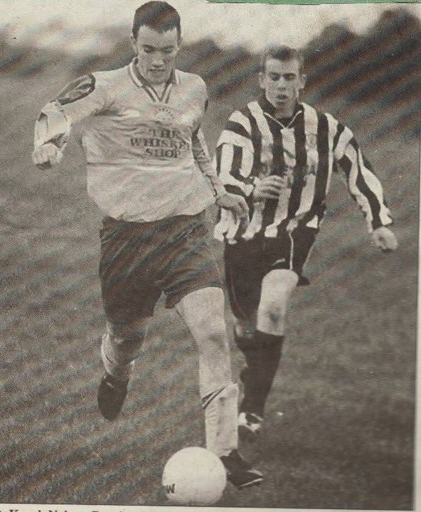 Crettyard United player in The Whiskey Shop kit racing a striped opponent