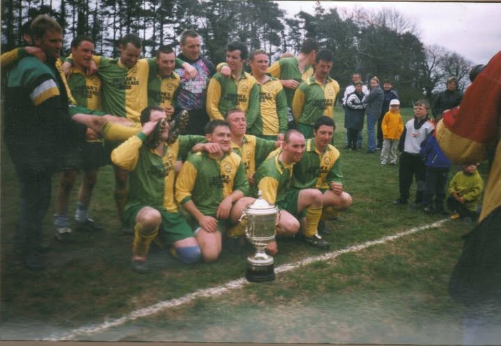 Crettyard United team celebrating with a trophy on the pitch