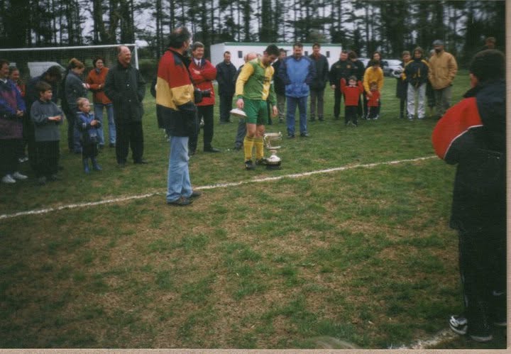 Crettyard United captain beside the trophy during a presentation on the pitch